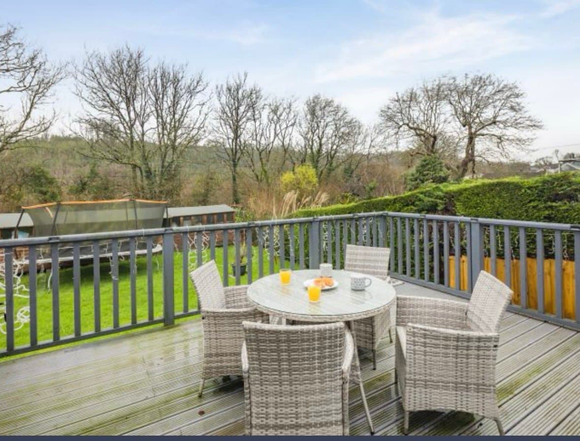 Spacious elevated deck with panoramic woodland views, featuring comfortable seating area and countryside vistas—perfect for peaceful mornings and al fresco dining.