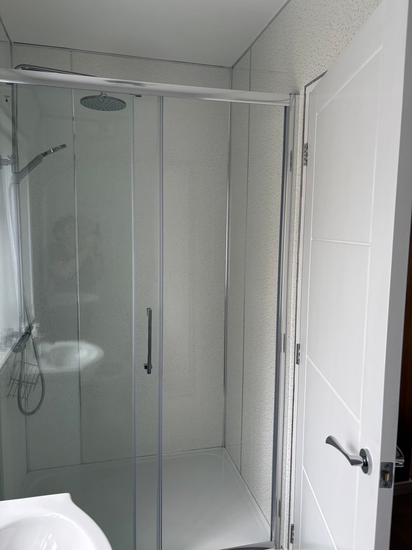 Modern ensuite shower room featuring a spacious walk-in enclosure with rainfall showerhead, sleek chrome fixtures, and contemporary tiling throughout.