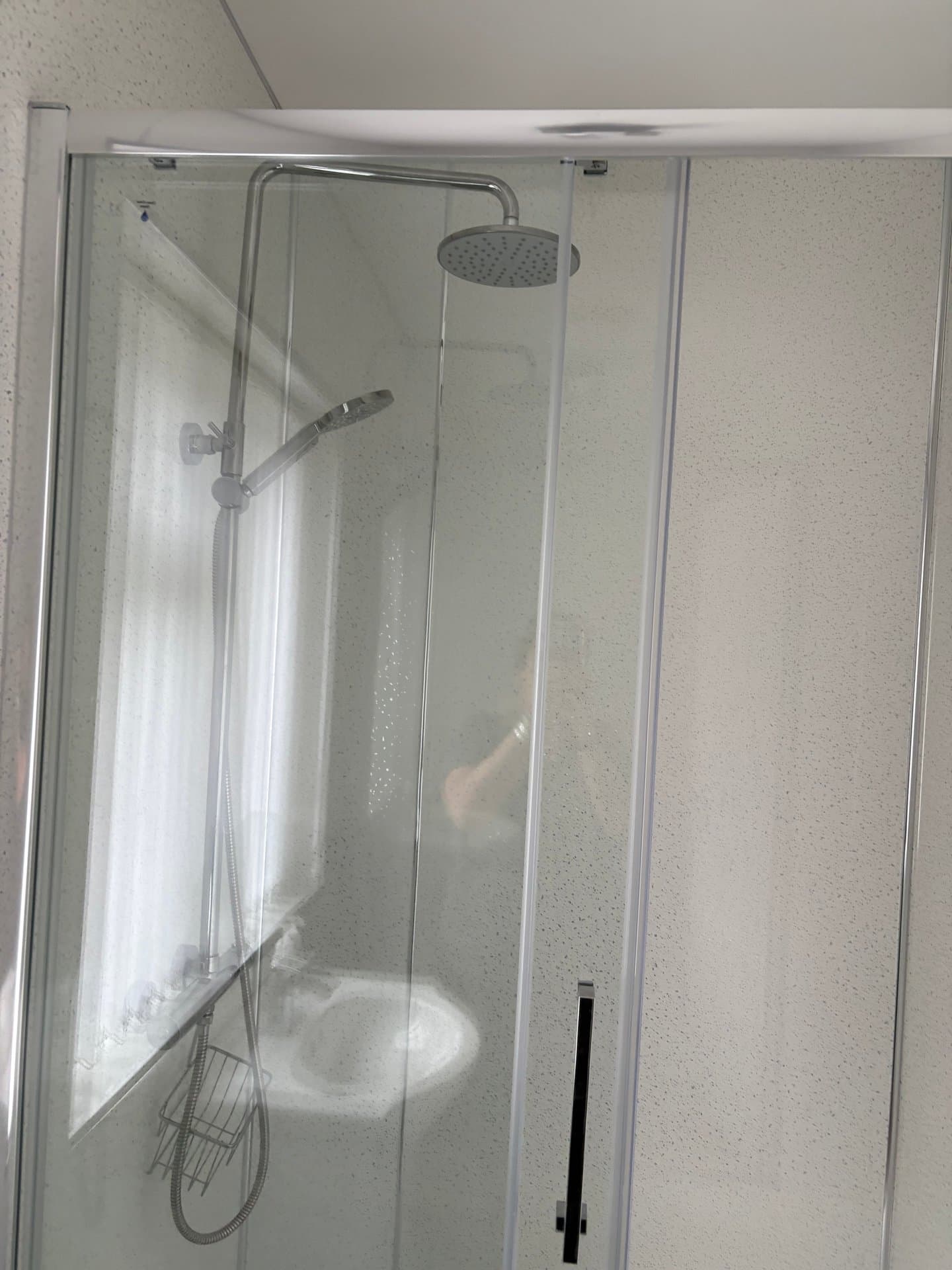 Modern shower enclosure with overhead rainfall showerhead and handheld shower, featuring sleek glass panels and contemporary fixtures for a refreshing bathroom experience.